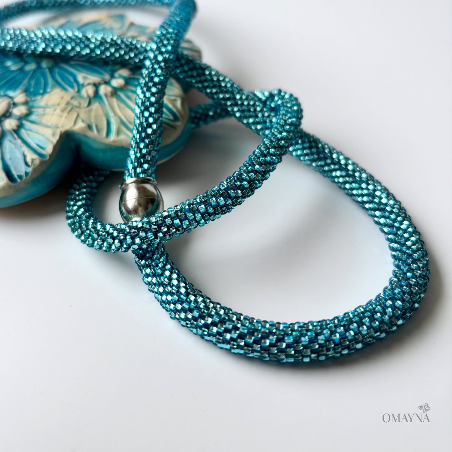 Turquoise beaded necklace and bracelet with a silver clasp on a light background