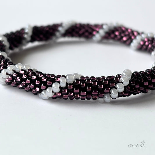 Beaded bracelet with purple and white beads on a white background - detail