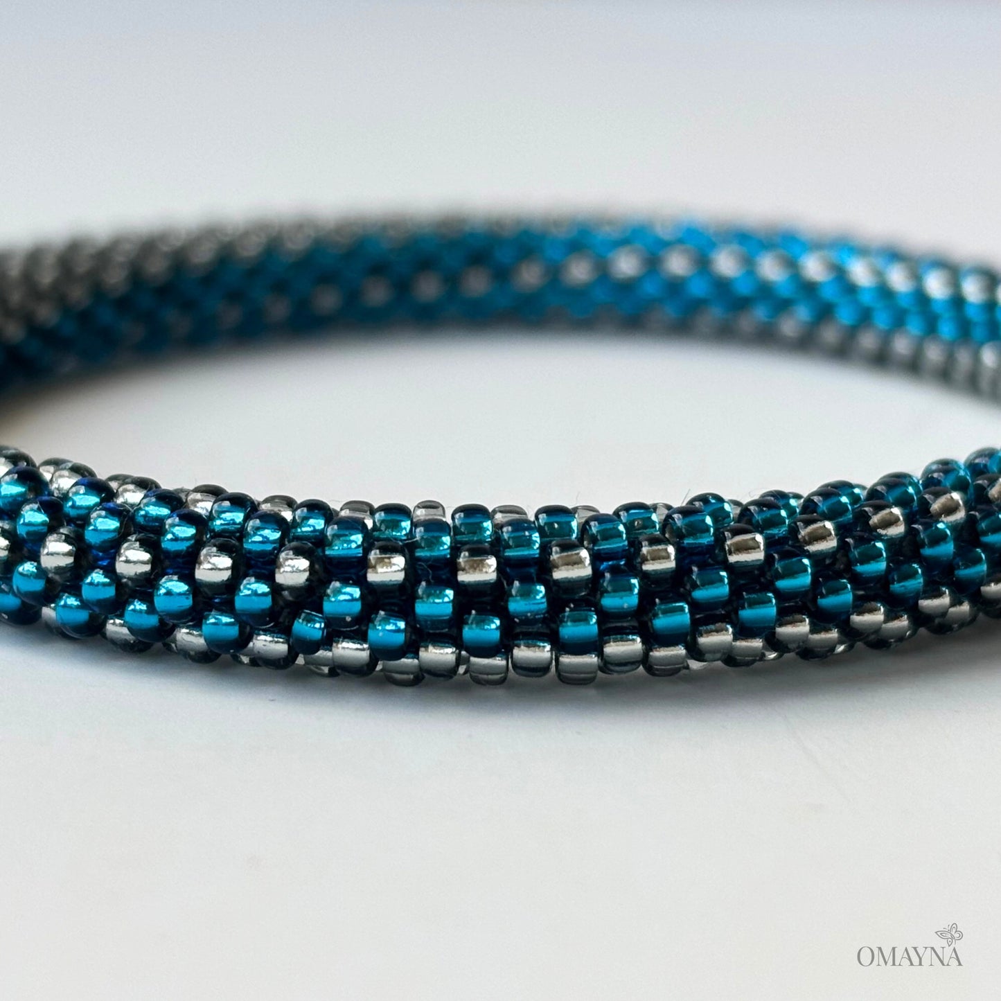Close-up of a blue and silver beaded bracelet on a light background