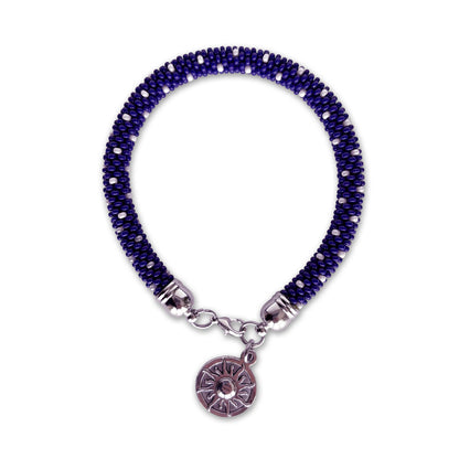 Cobalt blue beaded bracelet with a silver charm on a white background