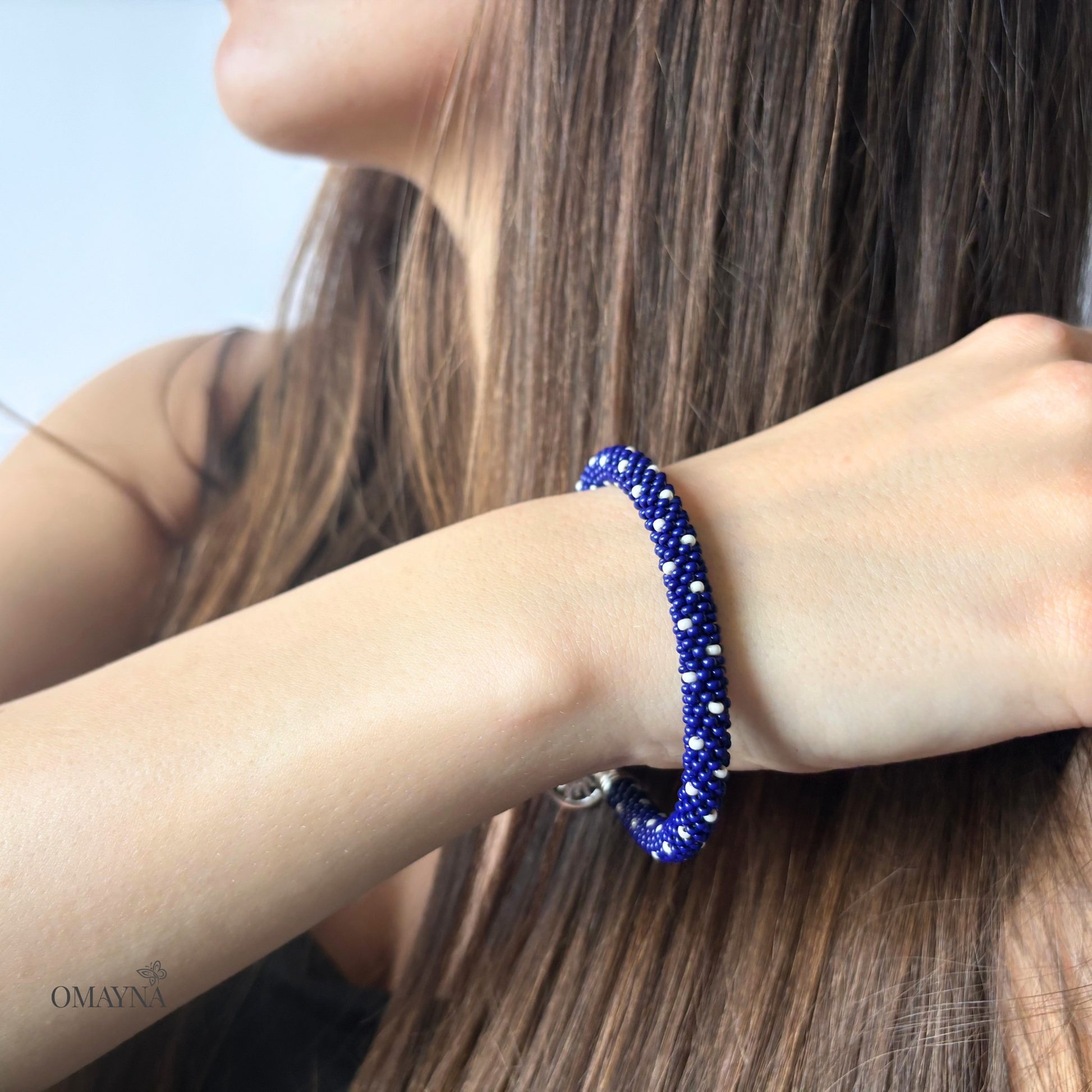 Person wearing a blue beaded bracelet on a light background