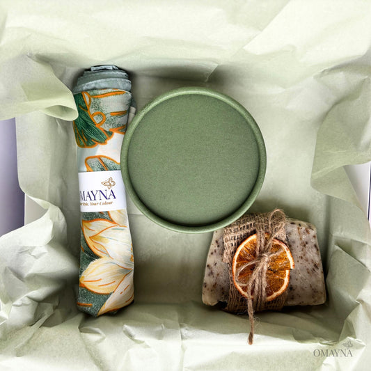 Product set with a green container, silk scarf, and artisan soap in a gift box with wrapping