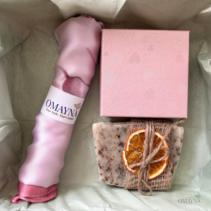 Pink scarf, soap with orange slices, and pink box on a light background