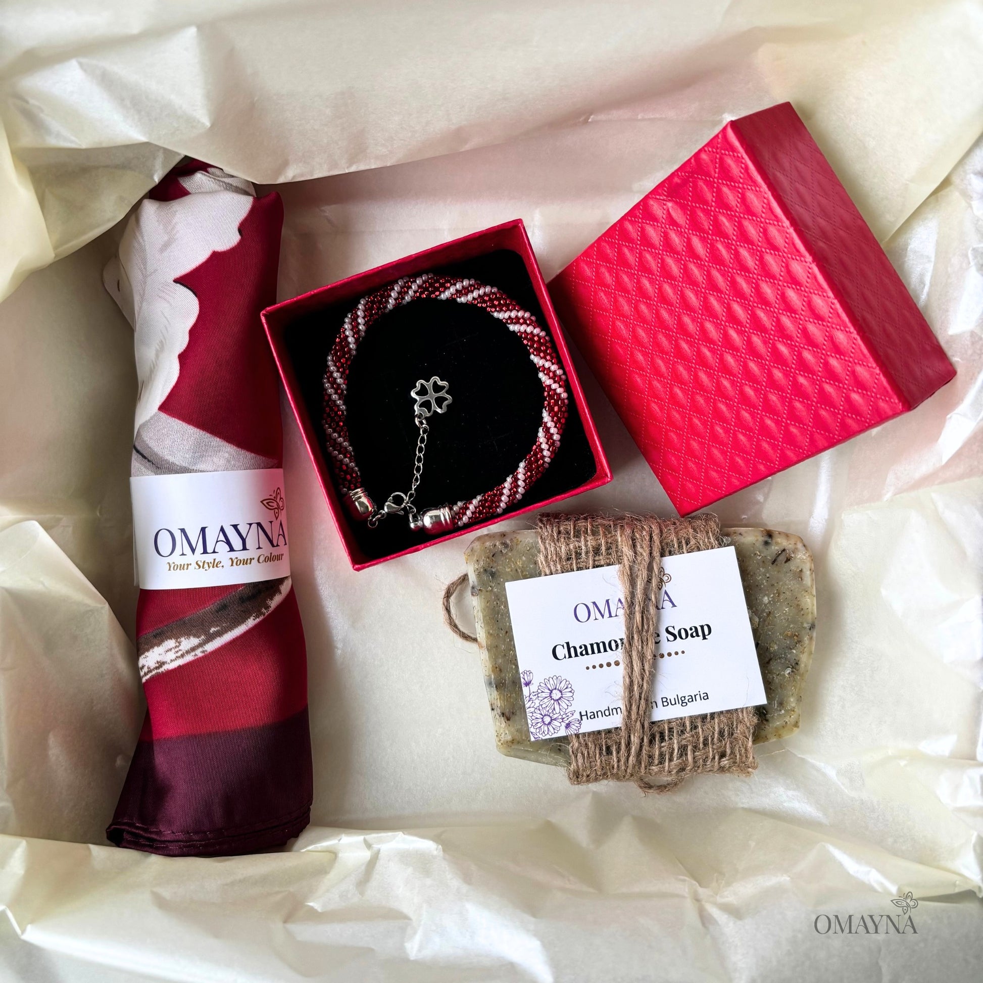 Gift set with bracelet, artisan soap, and silk scarf from Omayna on a white background