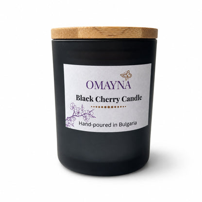 Black cherry candle with a wooden lid and Omayna label on a white background