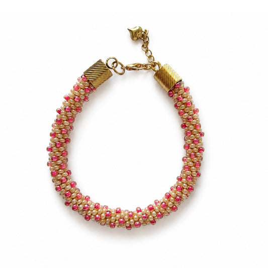 Beaded bracelet with pink and beige, gold-tone lobster clasp on a white background