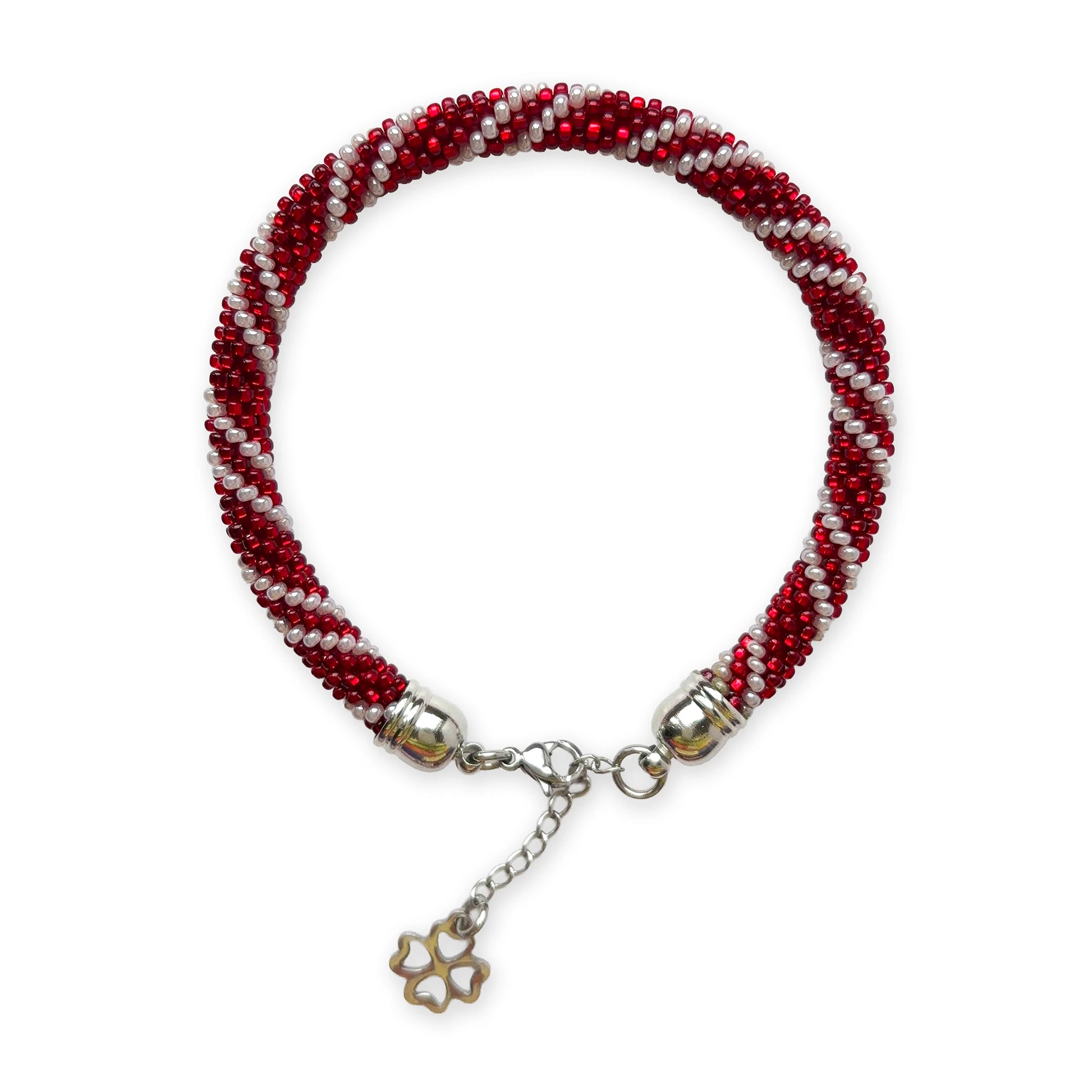 Beaded bracelet in red and pearl with a silver clove charm on a white background