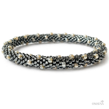 Multistrand beaded bracelet with metallic and pearl-like beads on a white background
