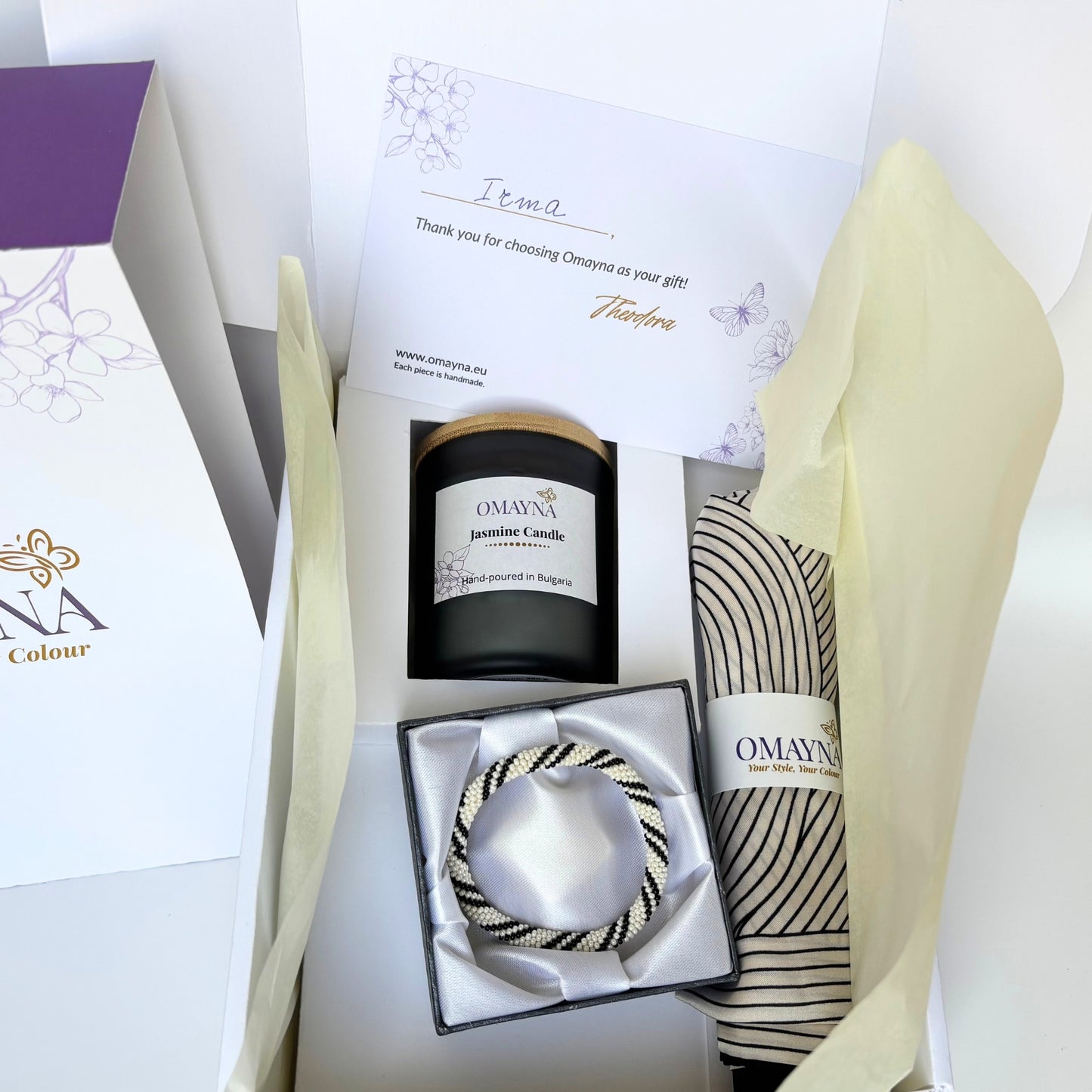 Gift set with jasmine candle, bracelet, and silk scarf from Omayna on a white background
