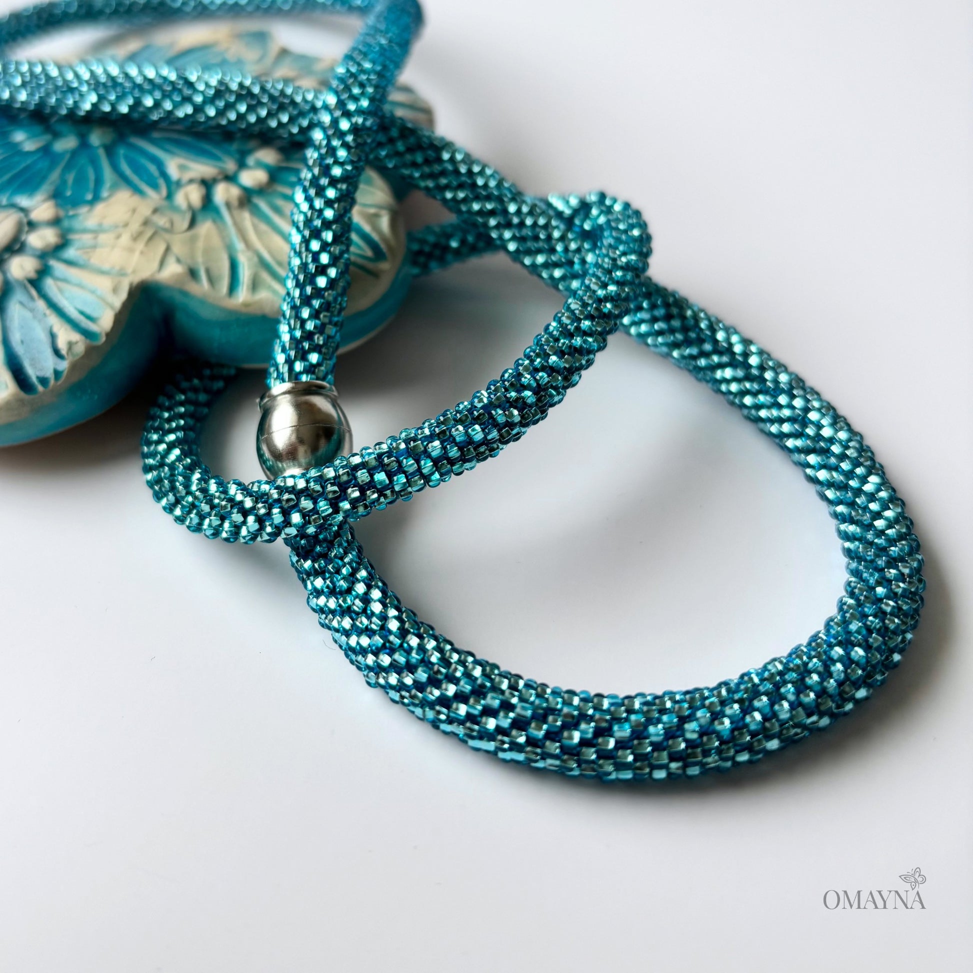 Turquoise beaded necklace and bracelet with a silver clasp on a light background