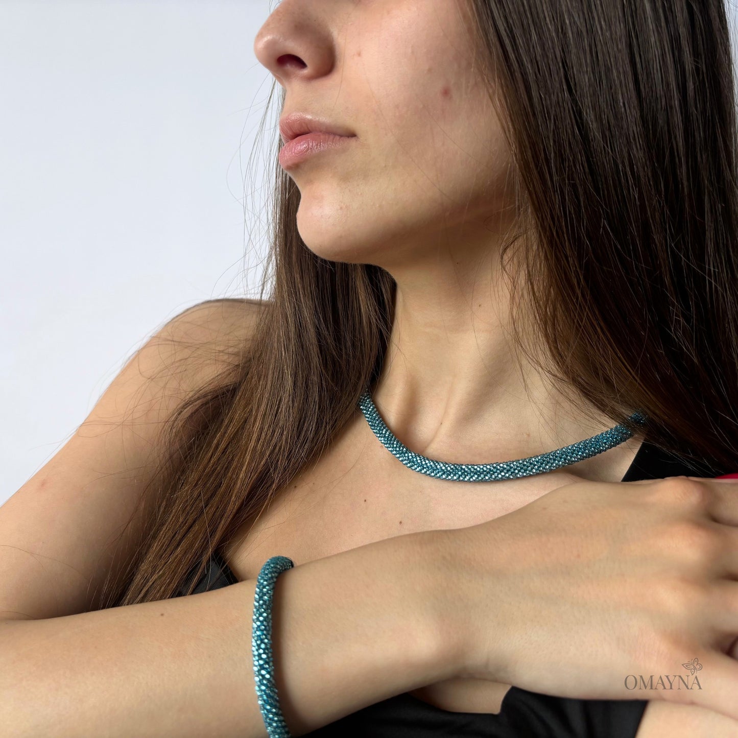 Woman wearing light blue Dara beaded necklace and bracelet against a light background