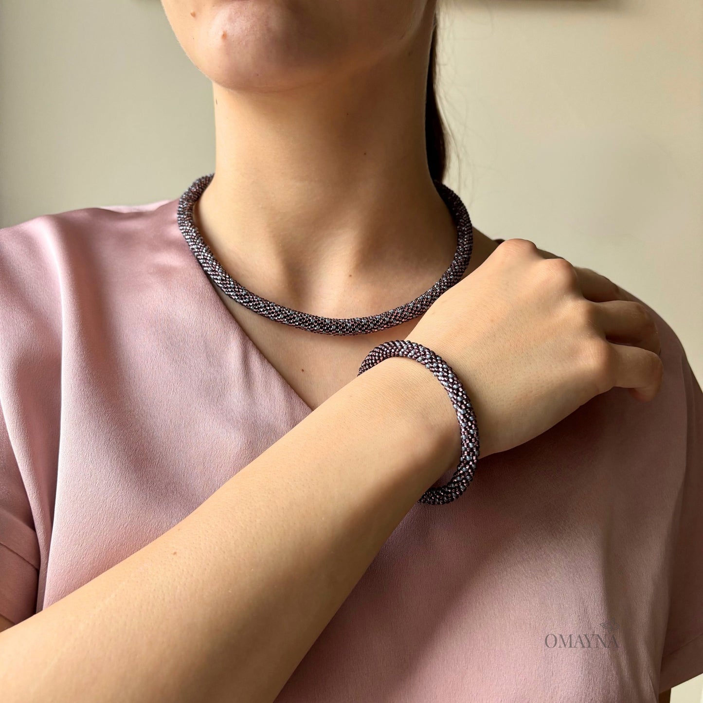Young woman wearing Eva set -  necklace and bracelet in light amethyst and gray on a plain background