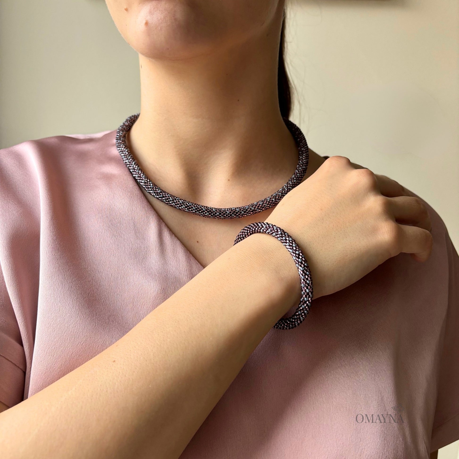 Young woman wearing Eva set -  necklace and bracelet in light amethyst and gray on a plain background