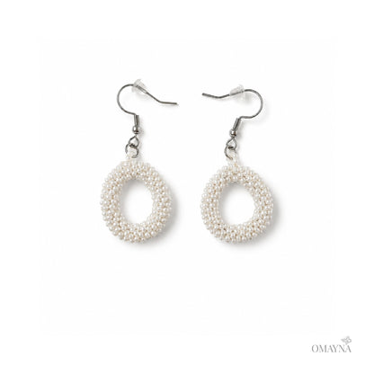 Pair of pearl earrings on a white background with 'OMAYNA' branding.