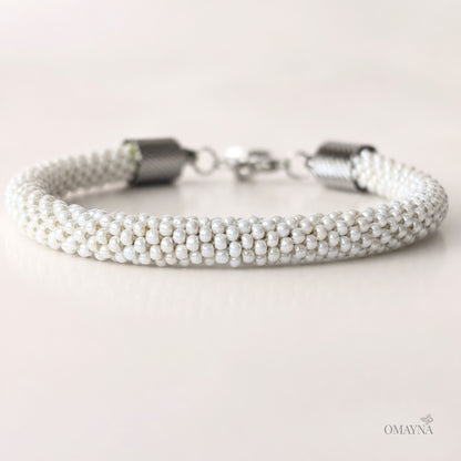 Pearl bracelet with silver clasp on a light background, featuring the brand 'OMAYNA'.