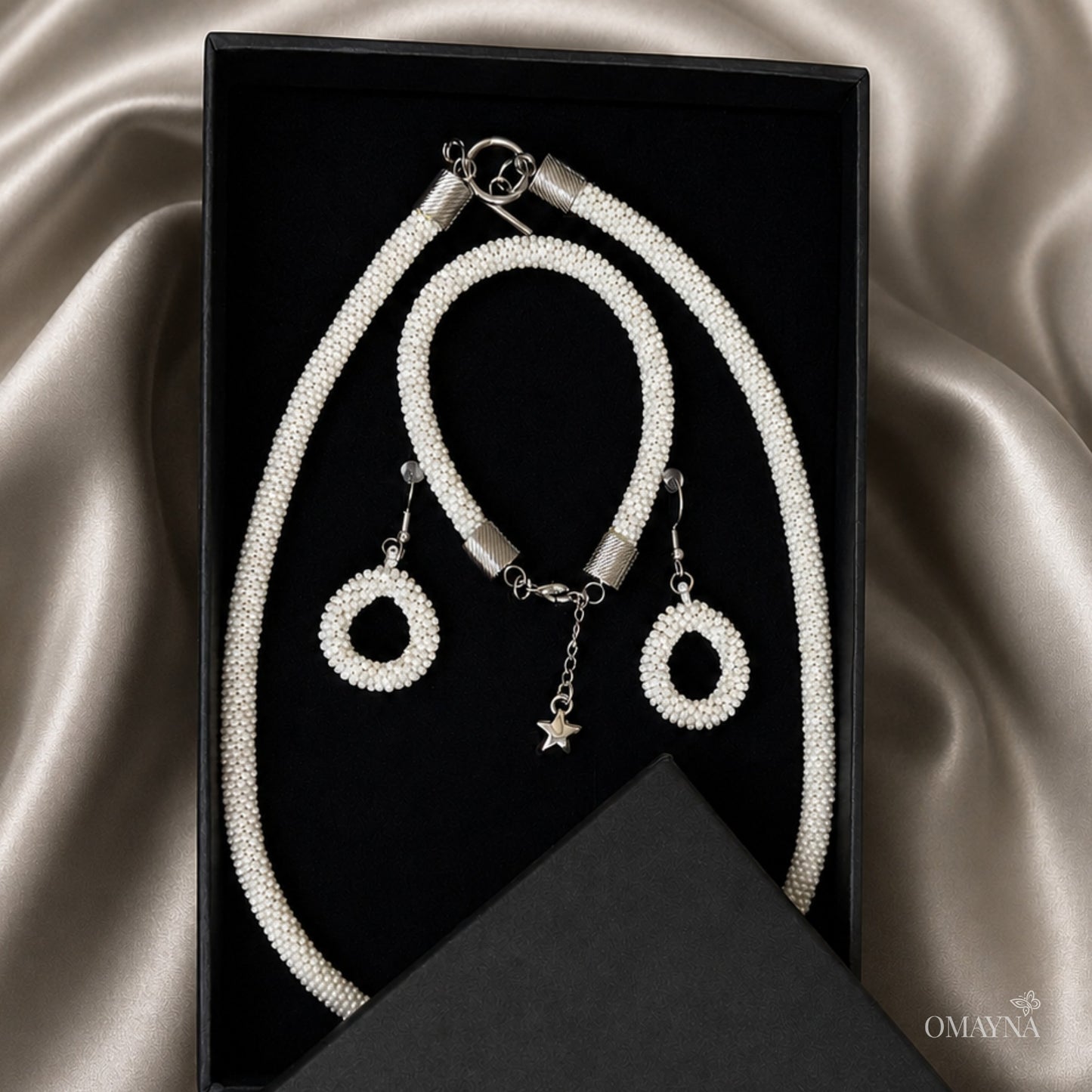 Jewelry set with necklace, bracelet, and earrings on a satin surface