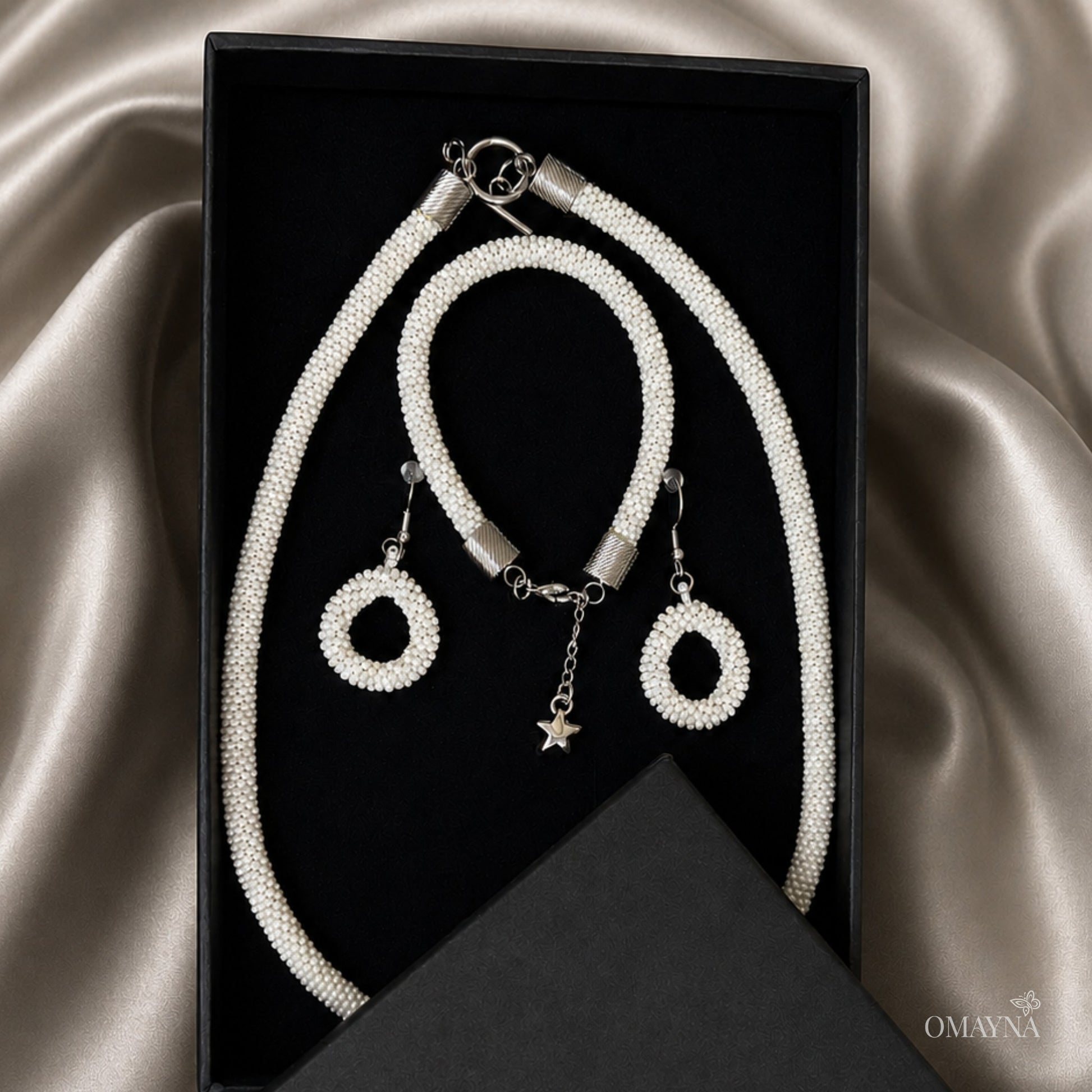 Jewelry set with necklace, bracelet, and earrings on a satin surface