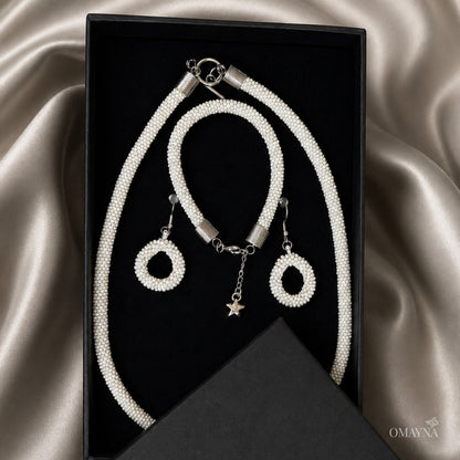 Jewelry set with necklace, bracelet, and earrings on a satin surface