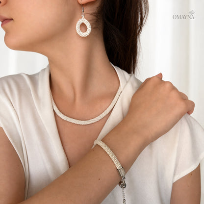 Woman wearing a necklace, bracelet, and earrings with a white background