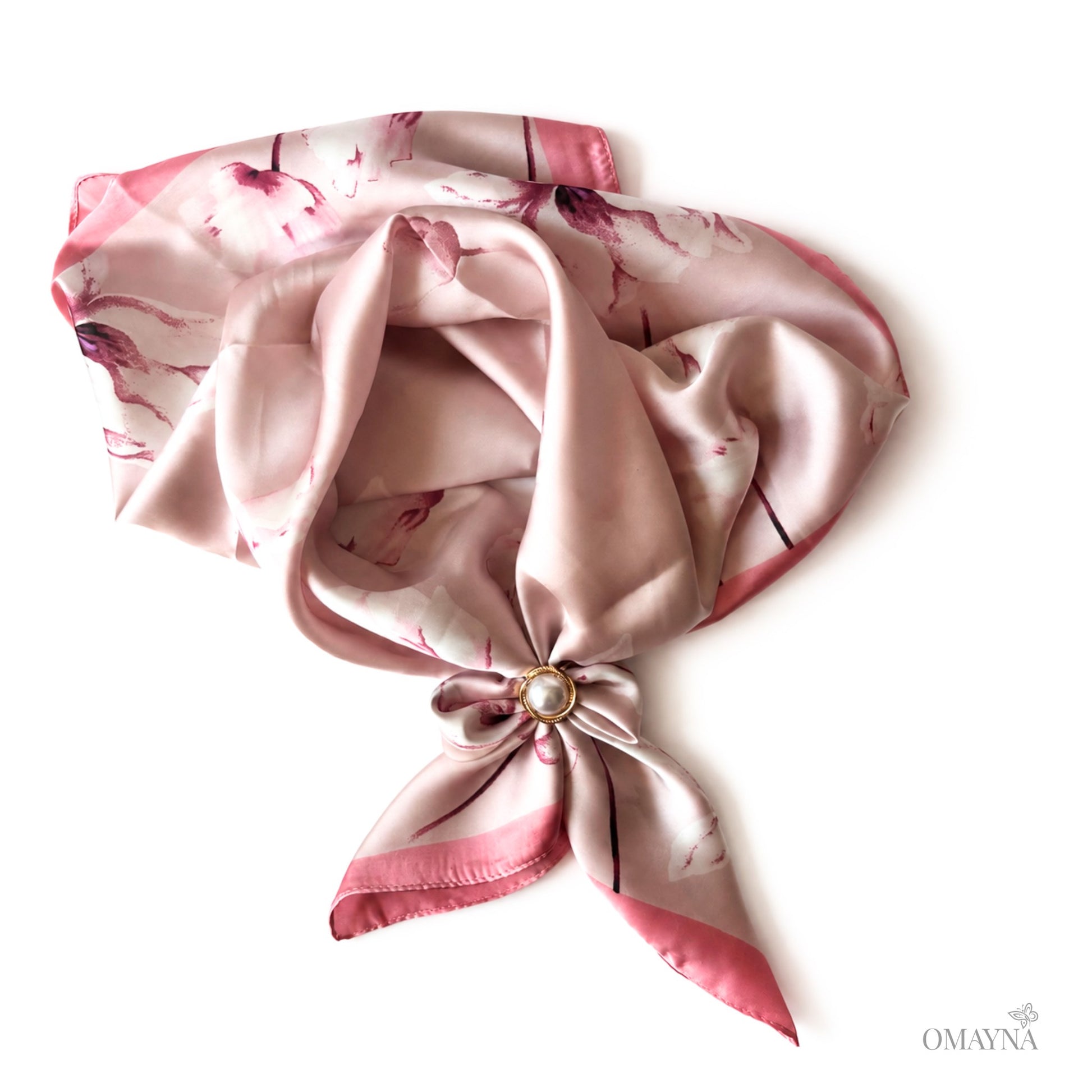 Pink floral patterned scarf with a knot and decorative pin on a white background