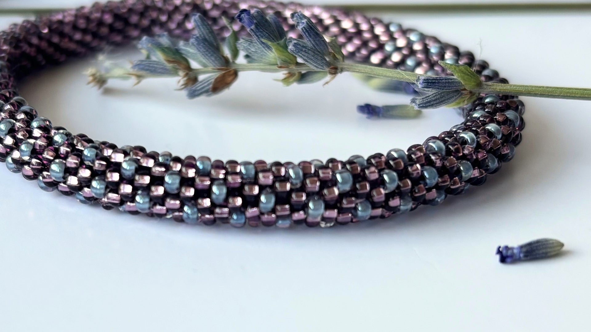 Multistrand beaded necklace with a sprig of lavender on a white background