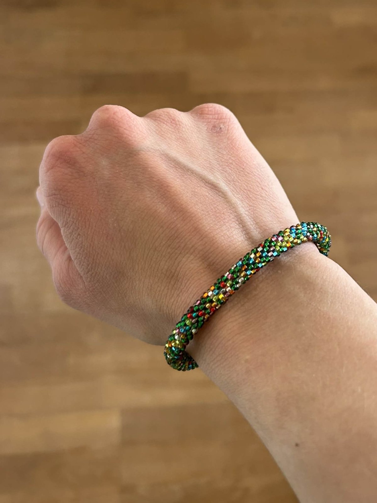Multicolored beaded bracelet on a wrist against a wooden background