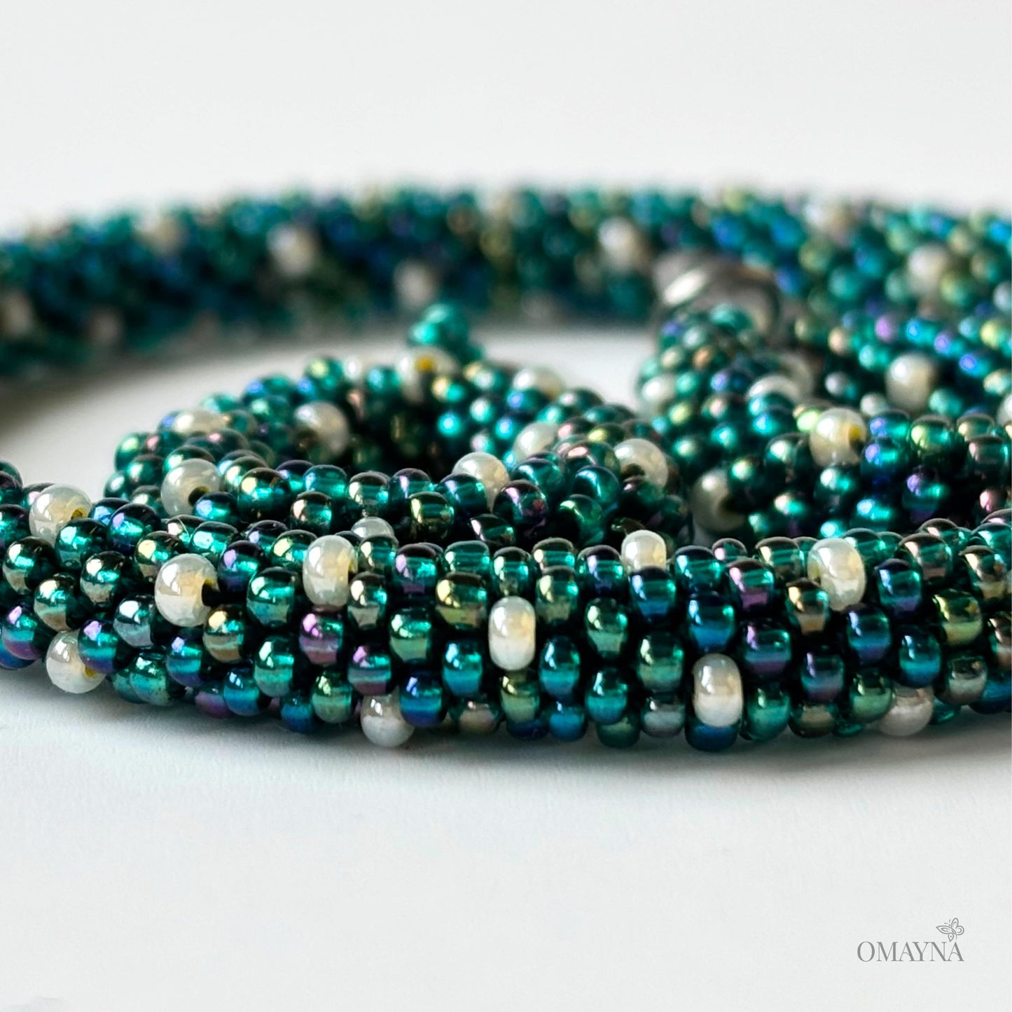 Close-up of Ivy - green iris and pearl beaded set of bracelet and earings on a light background