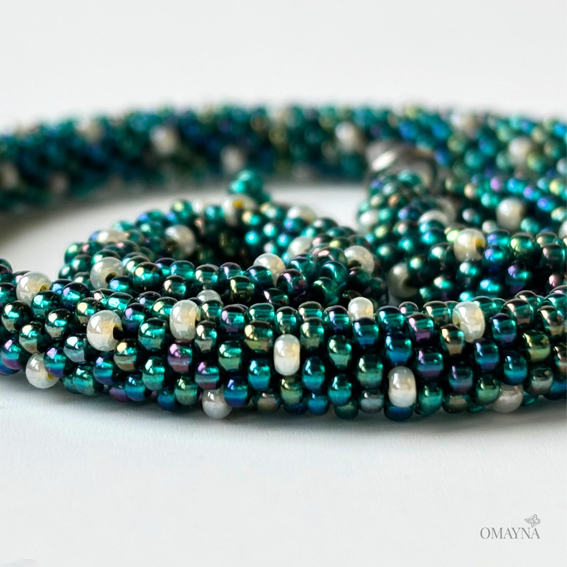 Close-up of Ivy - green iris and pearl beaded set of bracelet and earings on a light background