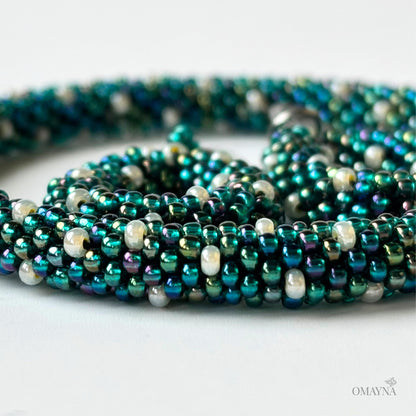 Close-up of Ivy - green iris and pearl beaded set of bracelet and earings on a light background