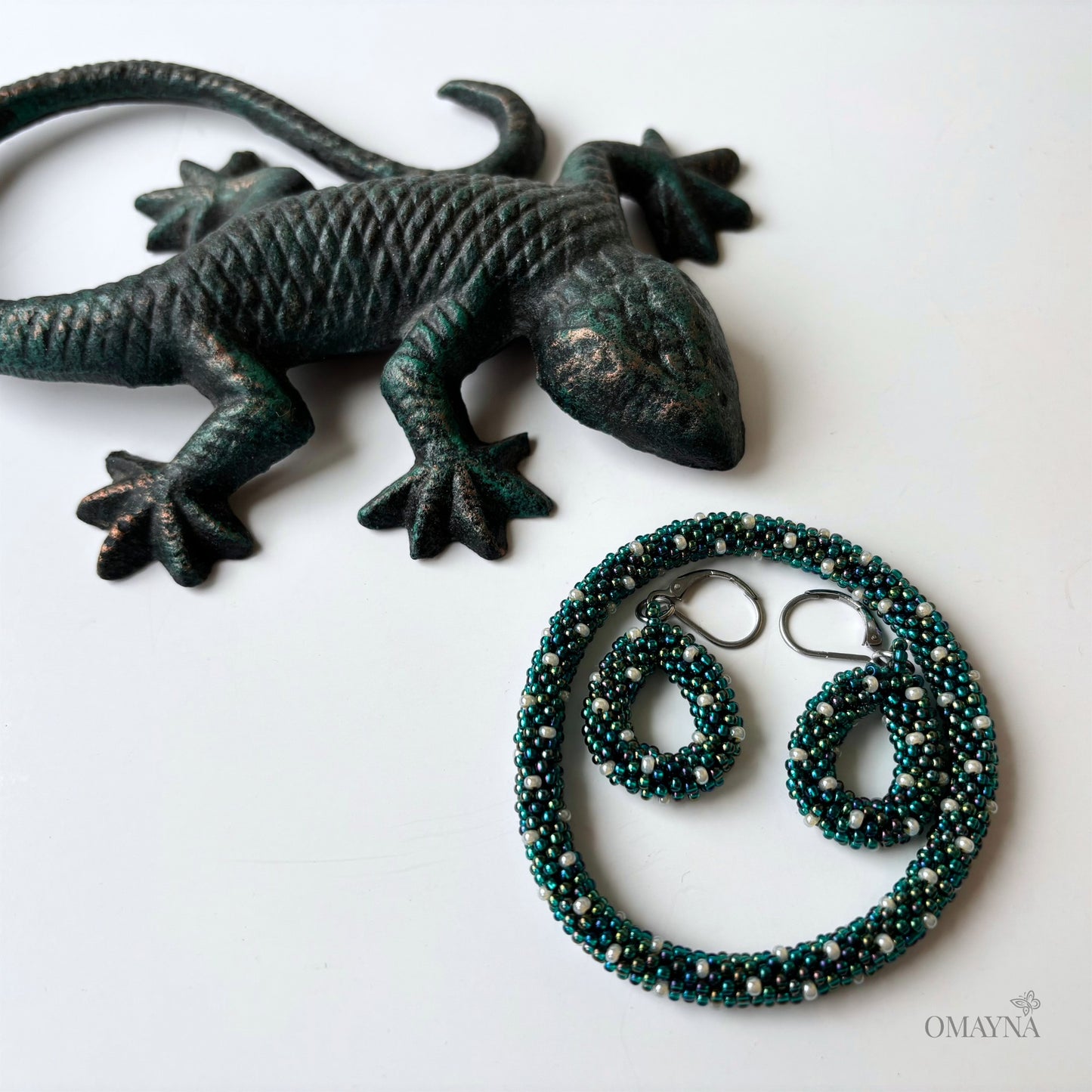Bronze lizard figurine with a bracelet and earrings on a white background