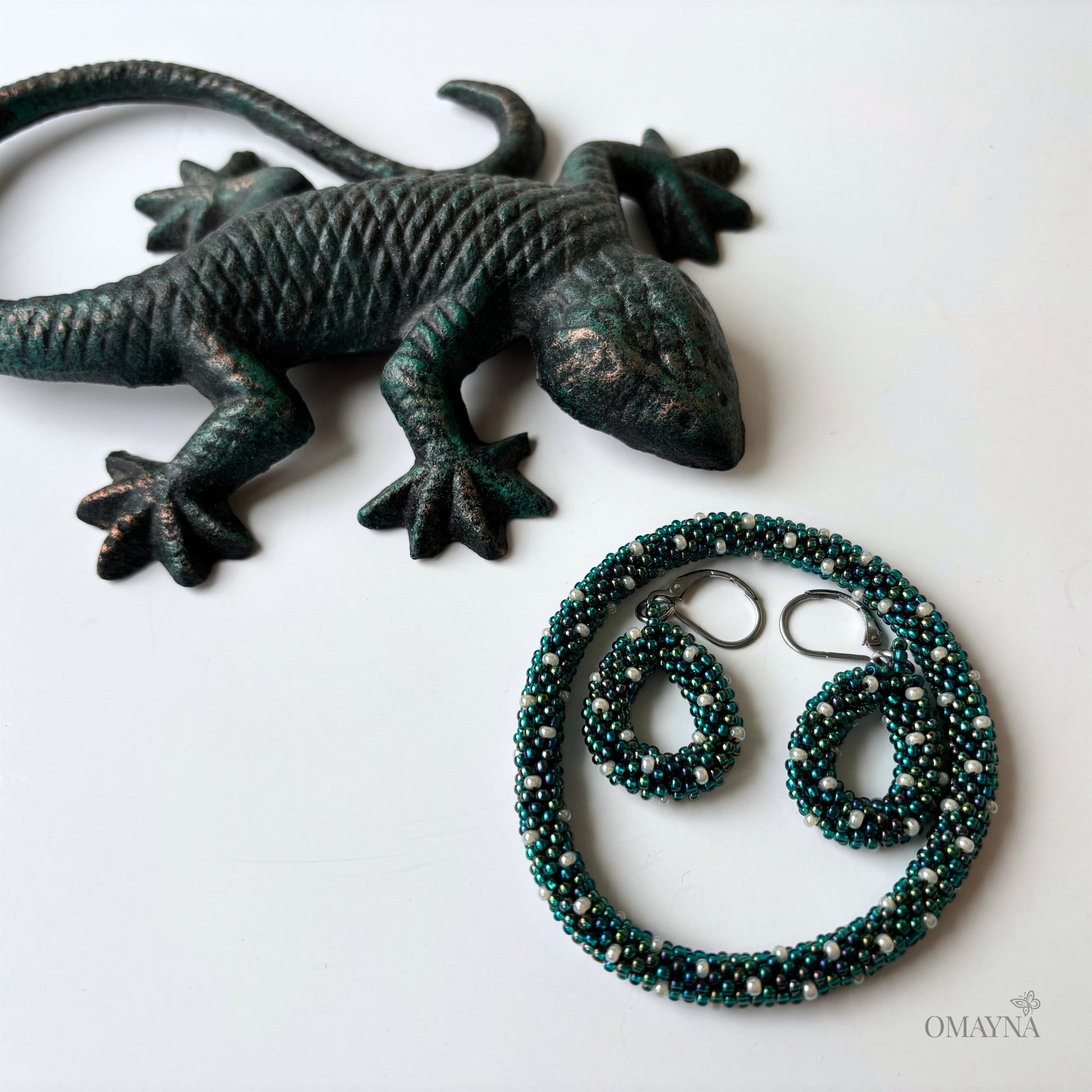 Bronze lizard figurine with a bracelet and earrings on a white background