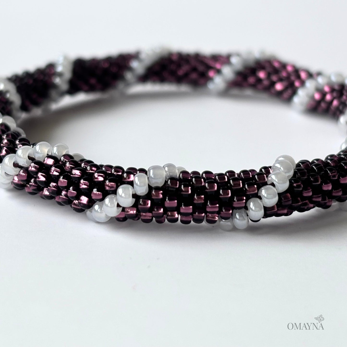 Beaded bracelet with purple and white beads on a white background - detail