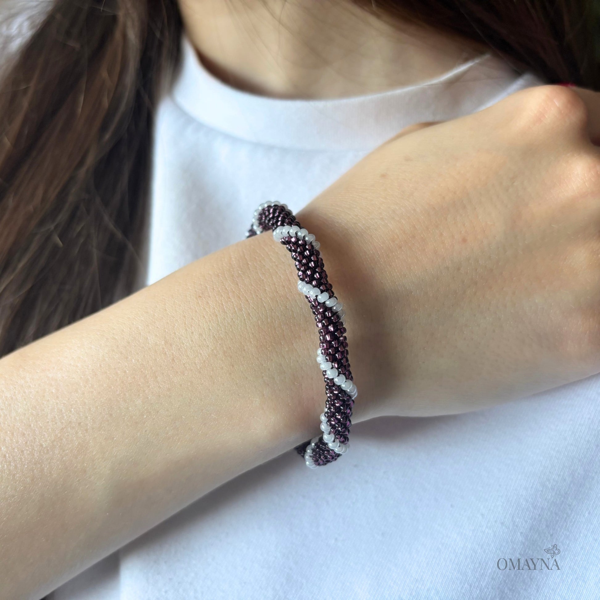 Close-up of a wrist wearing a beaded bracelet in purple and white