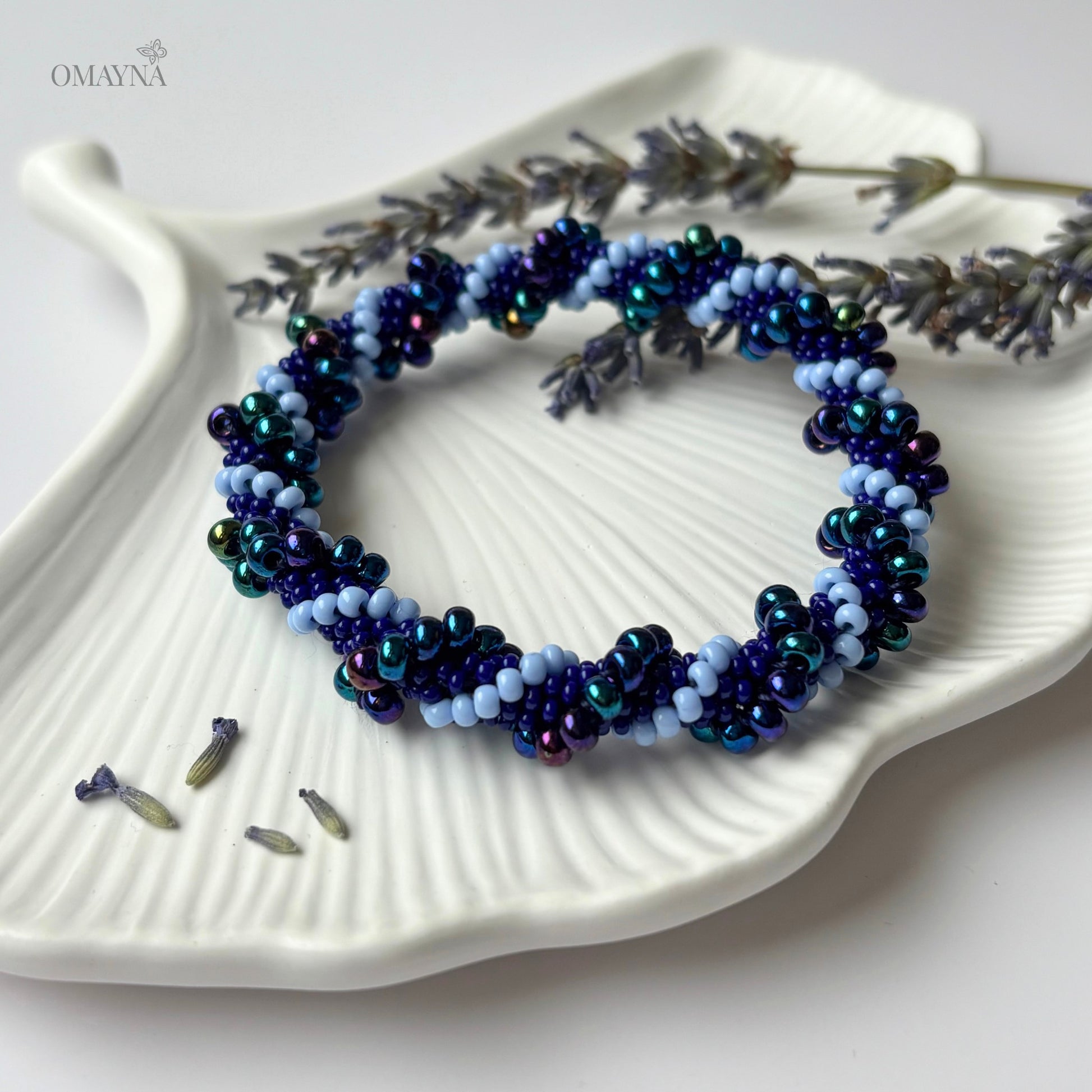 Beaded bracelet Mia - mixed shades of purple, on a white jewellery tray with lavender flowers