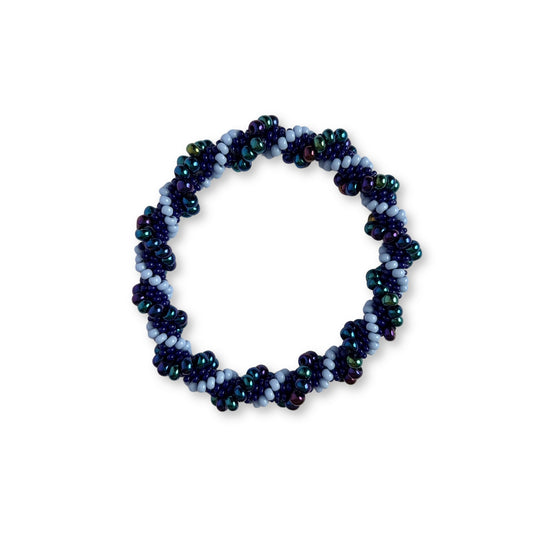 Beaded bracelet with different shades of purple beads on a white background