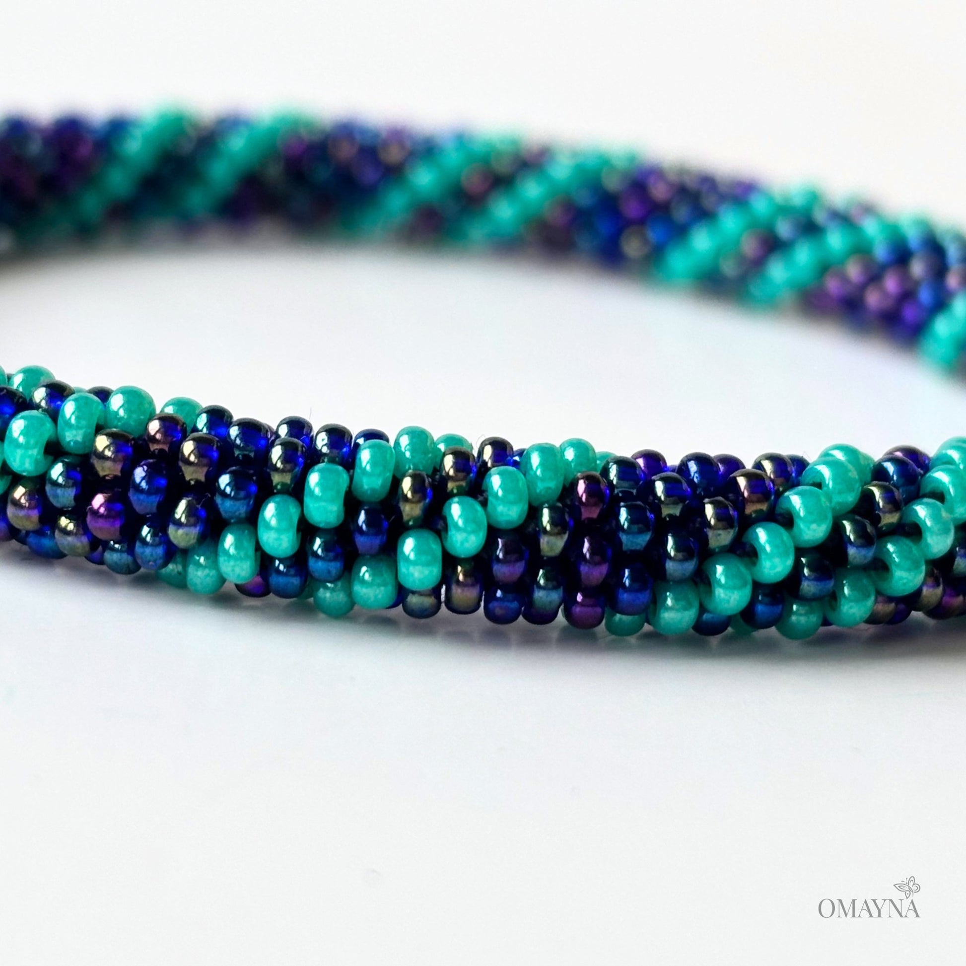 Nadya beaded bracelet with turquoise and purple beads on a white background, featuring the brand 'OMAYA'.