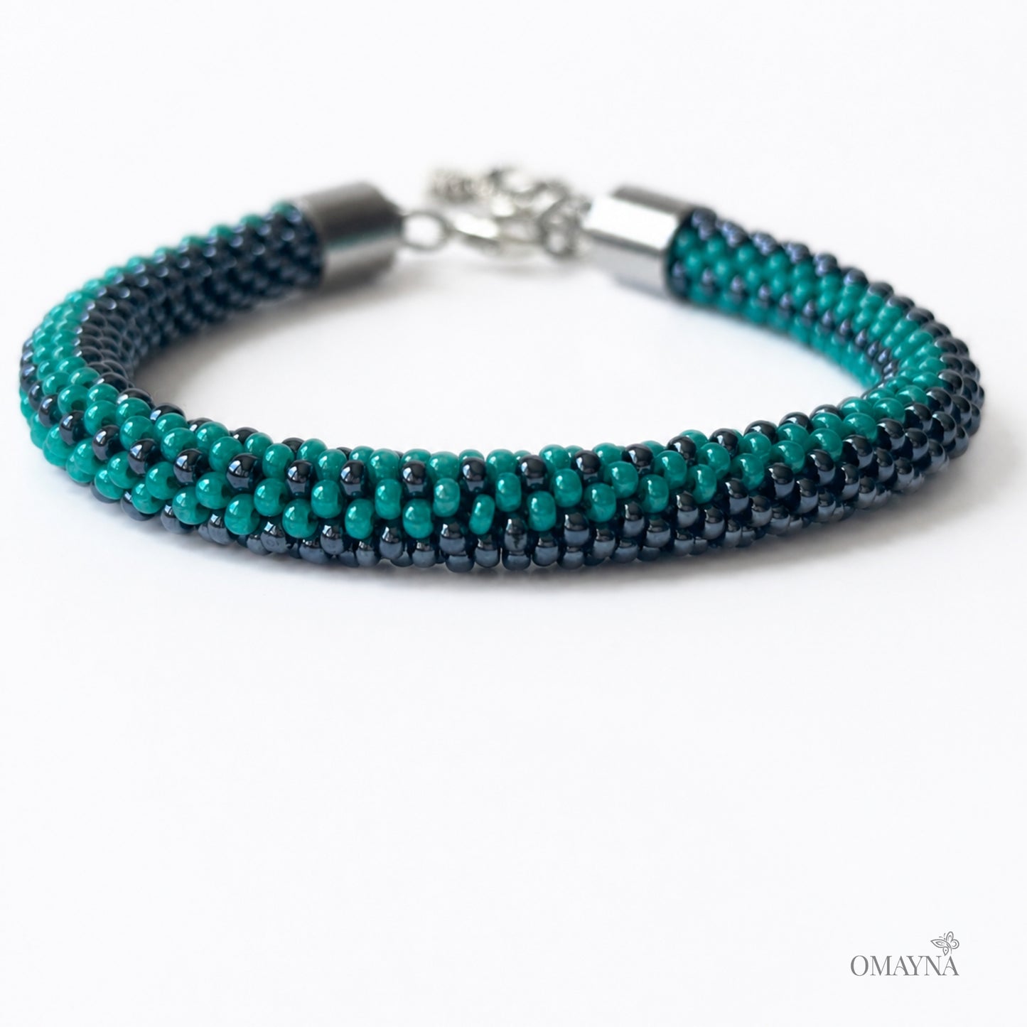 Multistrand beaded bracelet in hematite and green with silver clasp on a white background, close-up