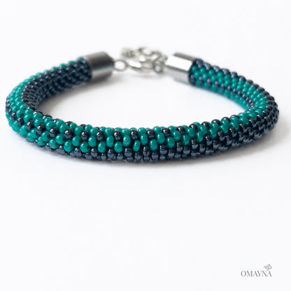 Multistrand beaded bracelet in hematite and green with silver clasp on a white background, close-up