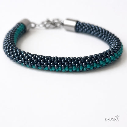 Multistrand beaded bracelet in hematite and green with silver clasp on a white background, close-up