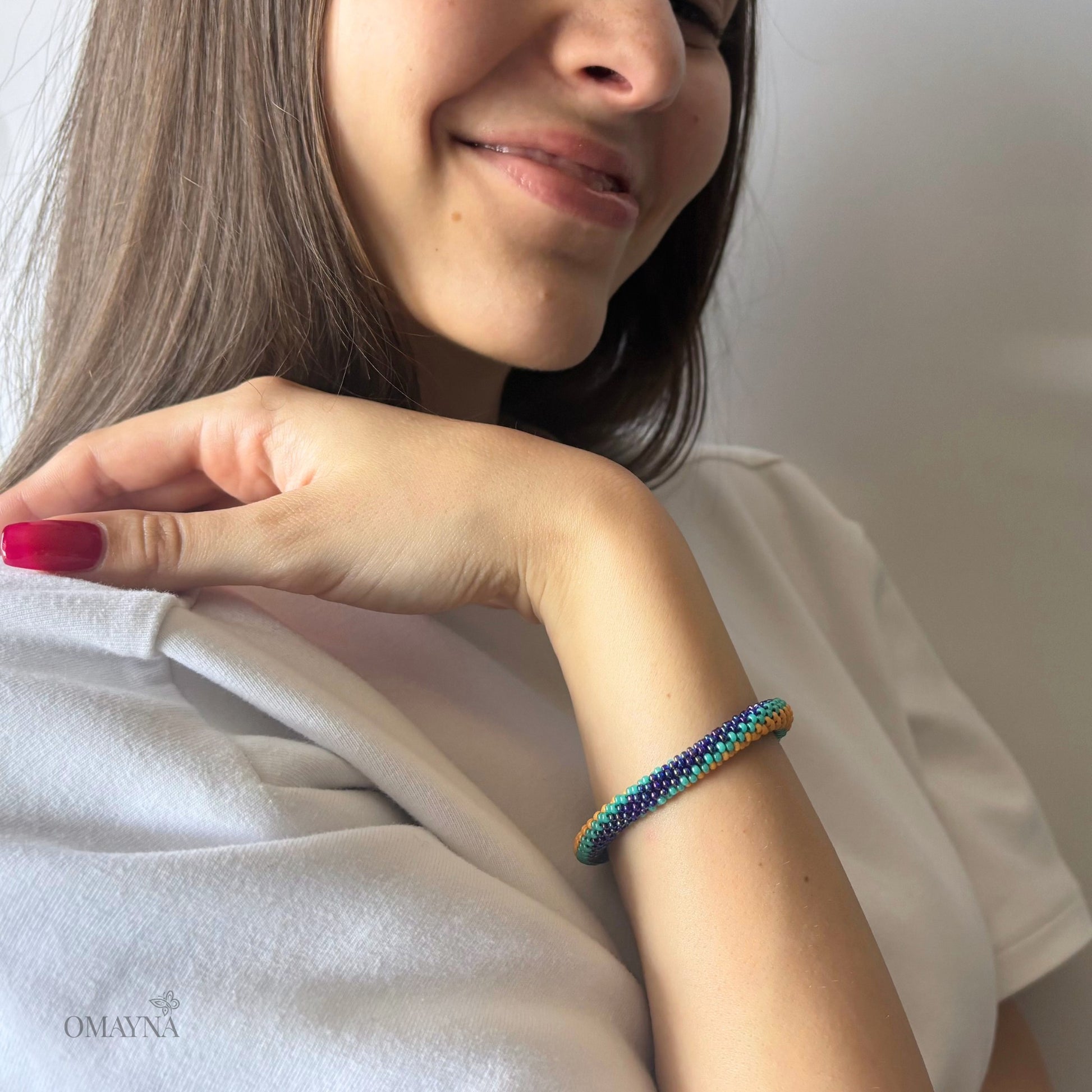 Woman wearing a colorful beaded bracelet on her wrist, with a neutral background.