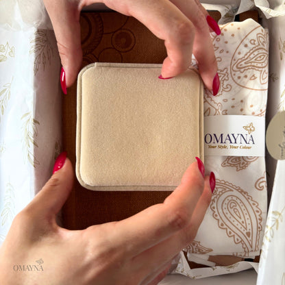 Beige jewellery box held by a hand with red nail polish, Omayna packaging in the background - Notebook set | Omayna