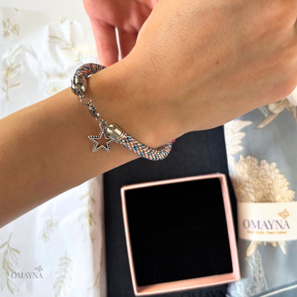 Bracelet with star charm on wrist next to Omayna packaging