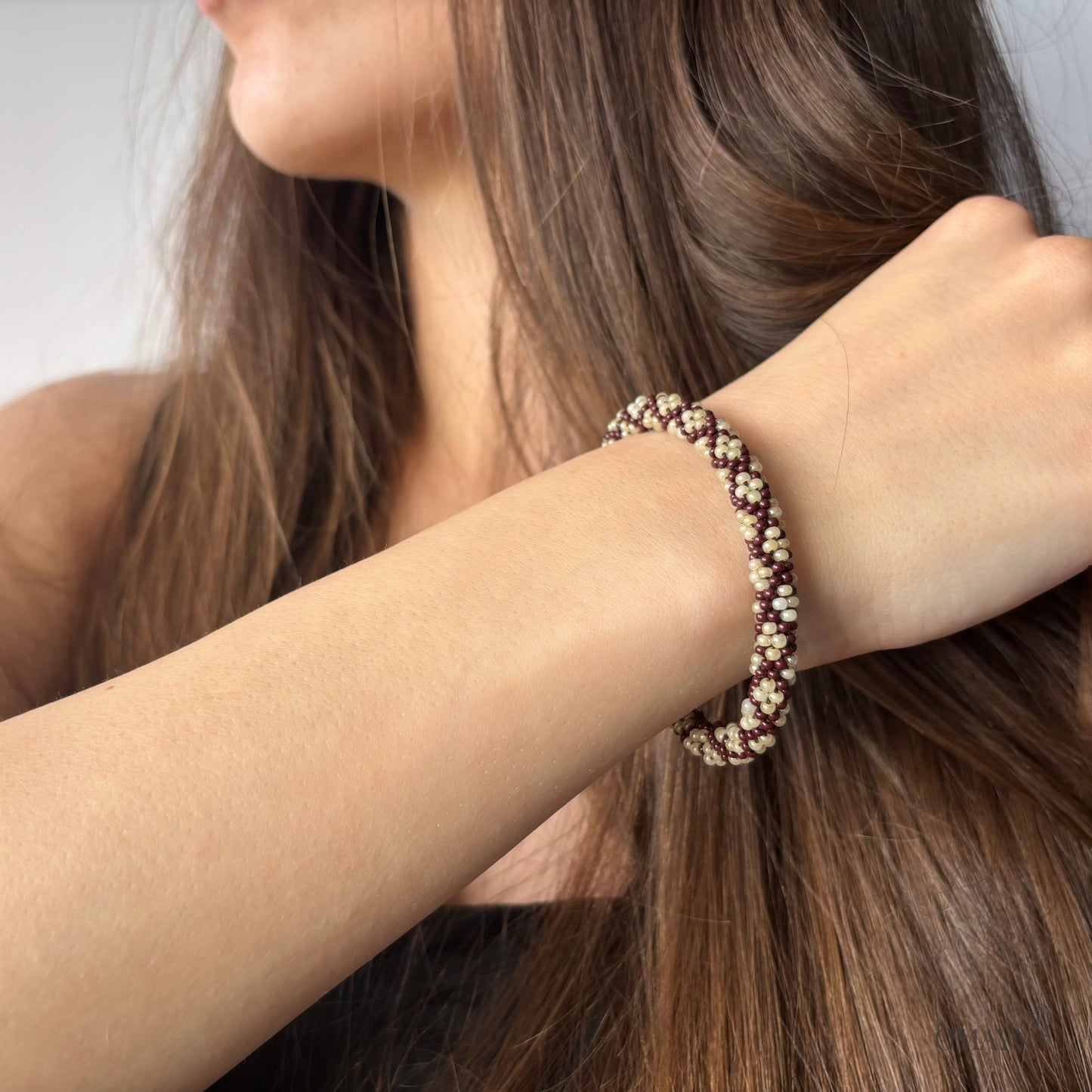Close-up of a person wearing a beaded bracelet on a plain background