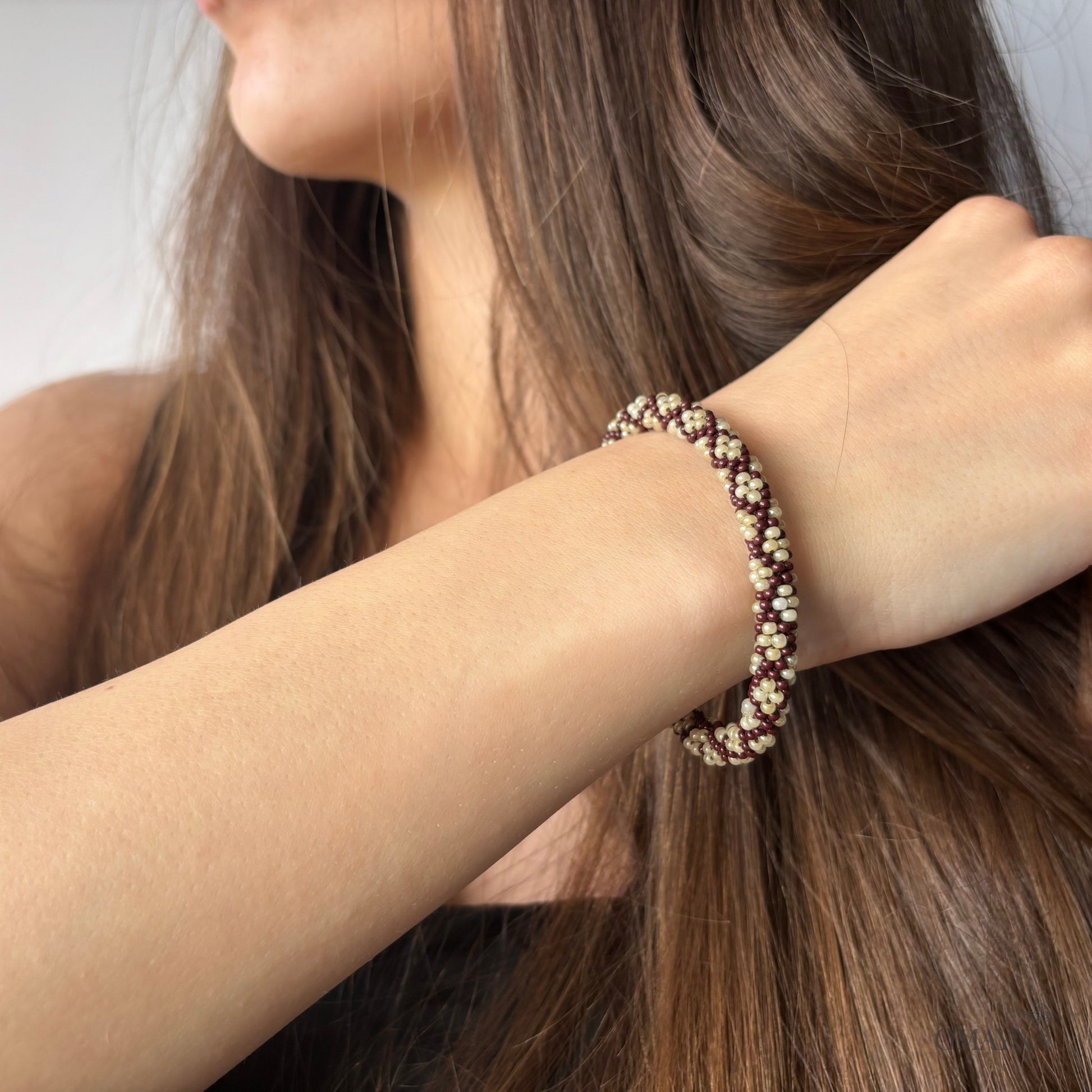 Close-up of a person wearing a beaded bracelet on a plain background