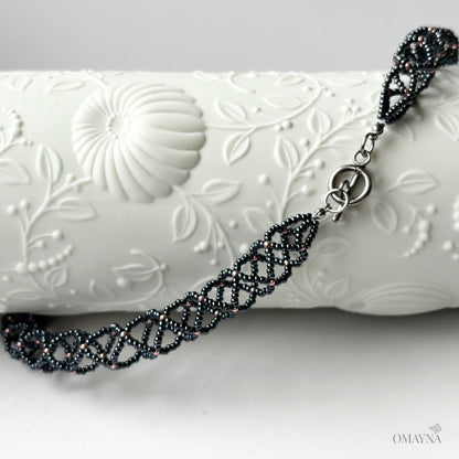 Close-up of Sofia beaded necklace in hematite & copper rose on a decorative element