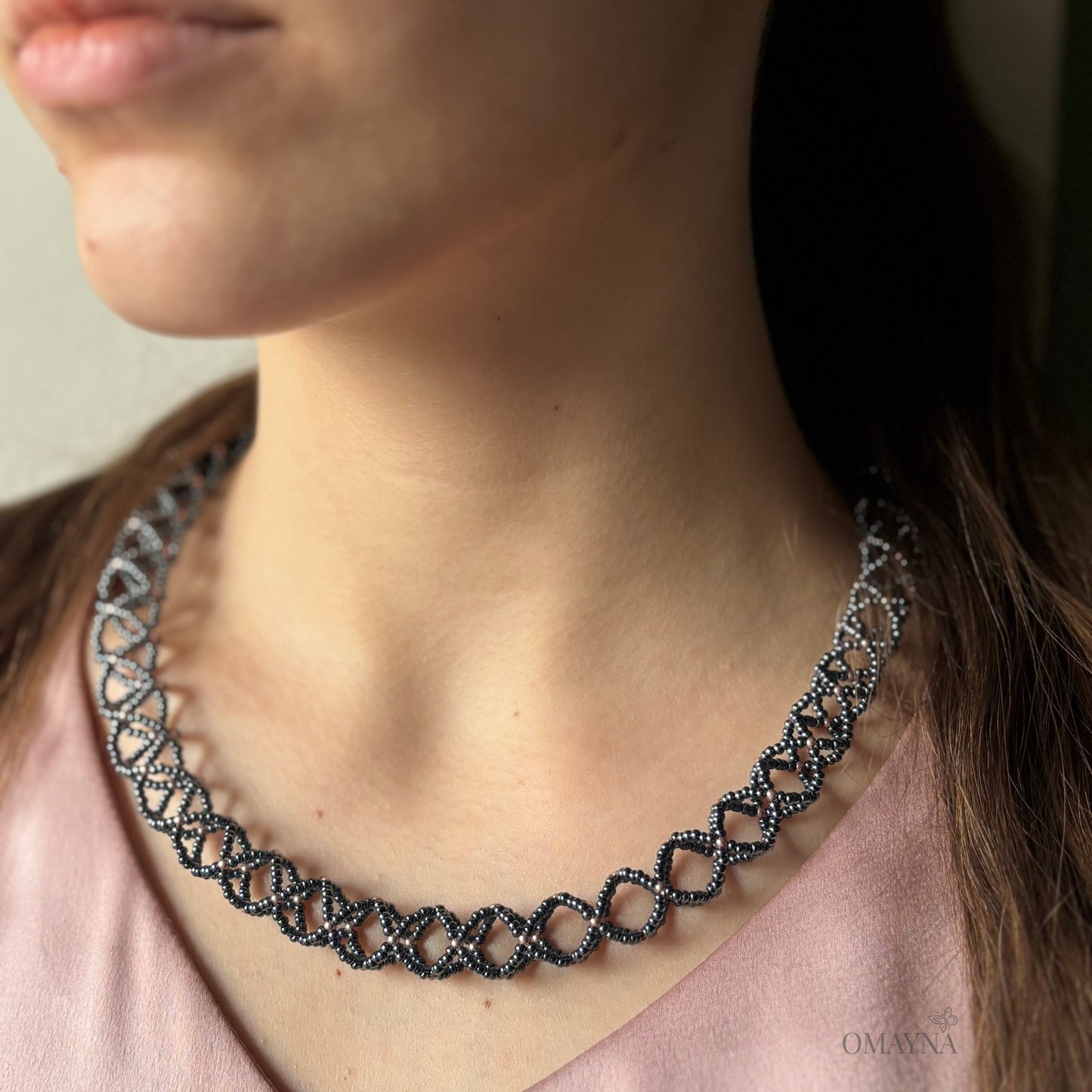 Close-up of a person wearing Sofia beaded necklace in hematite & copper rose