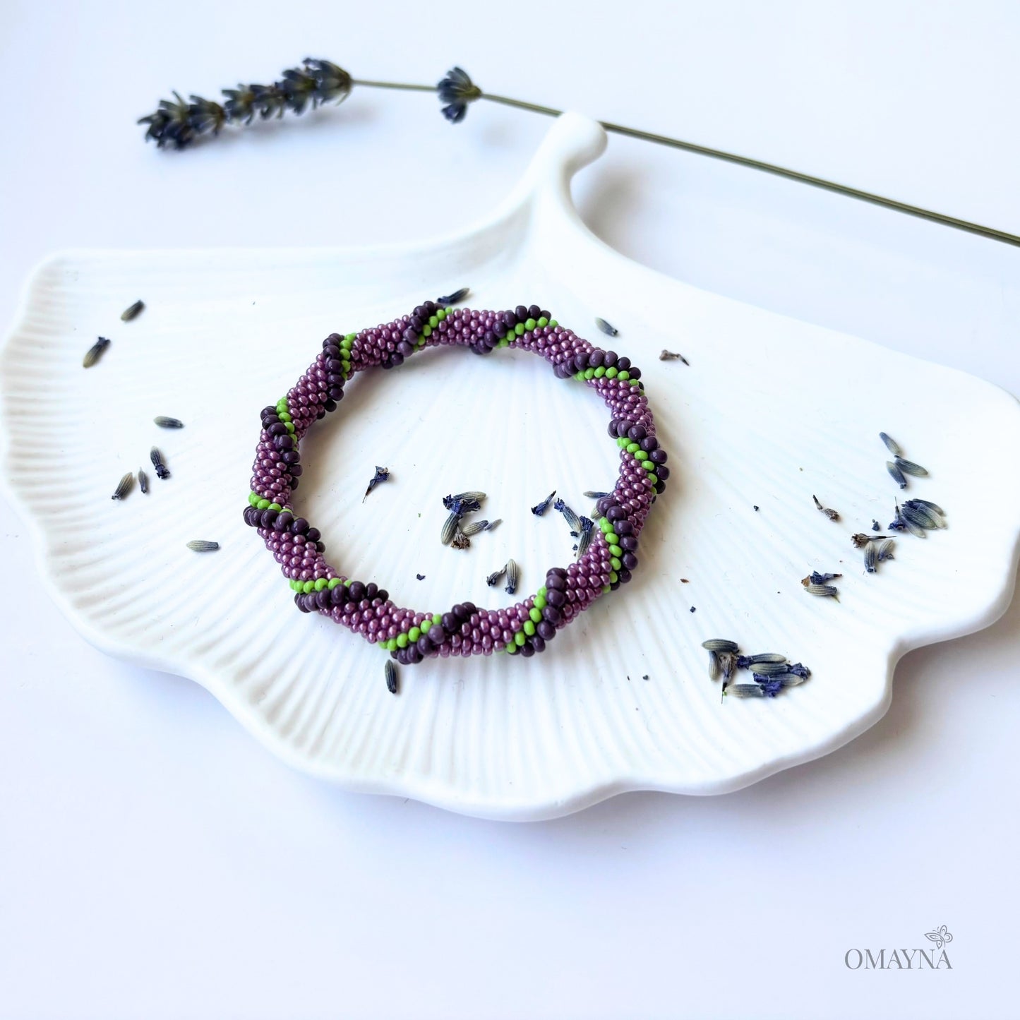 Purple and green beaded bracelet on a white jewellery tray with lavender flowers
