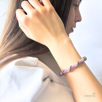 Woman wearing a colorful bracelet on her wrist with a plain background