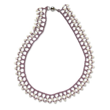 Una beaded necklace in soft purple and cream tones on a white background