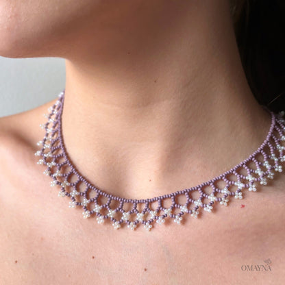Una beaded necklace in soft purple and cream tones worn by a young lady